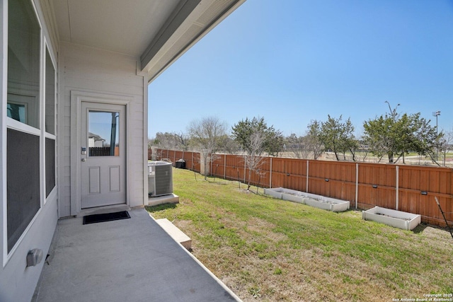 view of yard featuring a garden, a patio area, a fenced backyard, and central air condition unit