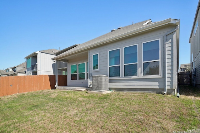 back of property featuring a lawn, fence, and central air condition unit