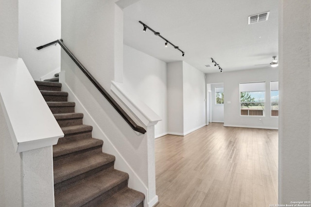 stairway featuring ceiling fan, wood finished floors, visible vents, and baseboards