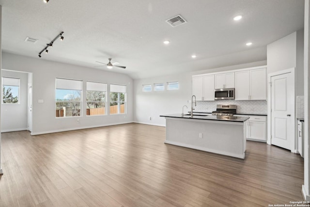 kitchen with stainless steel appliances, open floor plan, visible vents, and backsplash