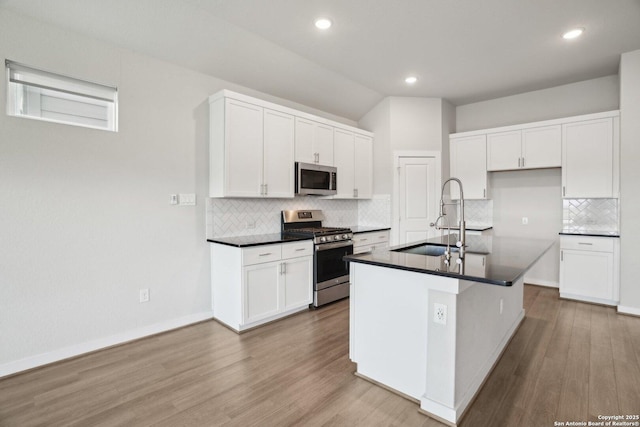 kitchen featuring dark countertops, white cabinetry, stainless steel appliances, and a sink