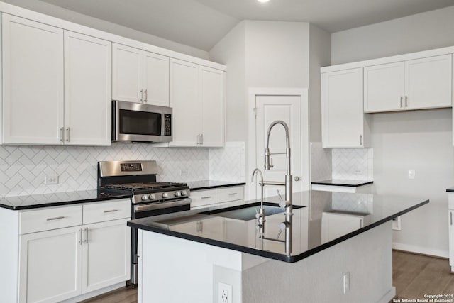 kitchen featuring stainless steel appliances, dark countertops, dark wood finished floors, and white cabinets