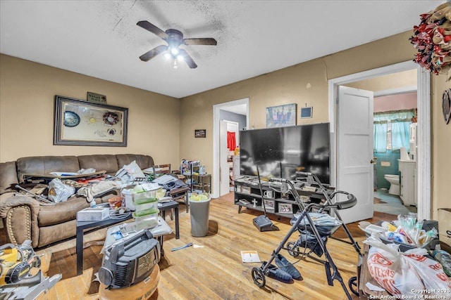 living area with light wood-style flooring, a textured ceiling, and a ceiling fan