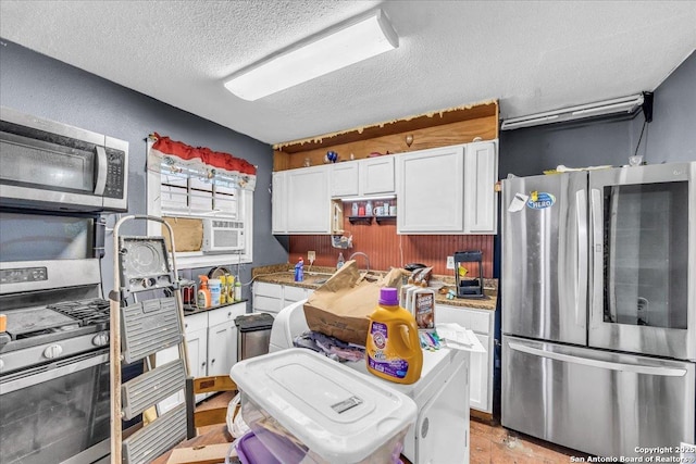 kitchen with cooling unit, appliances with stainless steel finishes, white cabinets, and a textured ceiling