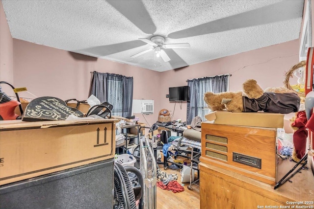 bedroom with a ceiling fan, a textured ceiling, and a wall mounted air conditioner