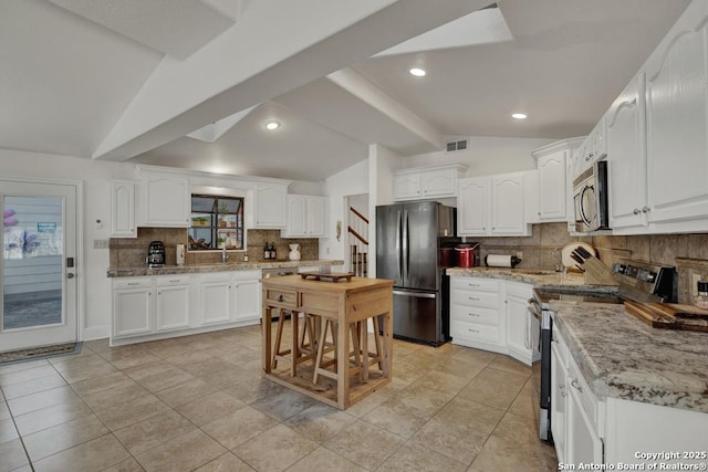 kitchen featuring stainless steel appliances, lofted ceiling, visible vents, and white cabinetry