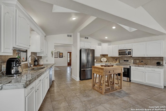 kitchen with a sink, visible vents, white cabinets, vaulted ceiling, and appliances with stainless steel finishes