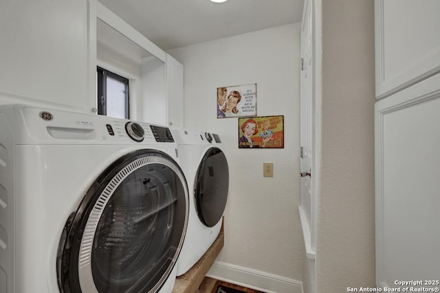 washroom with cabinet space, baseboards, and independent washer and dryer