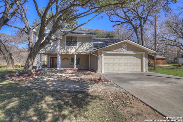 traditional-style home featuring a garage, covered porch, driveway, and a front yard