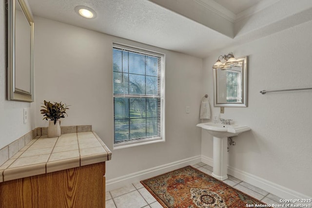 bathroom featuring a textured ceiling, tile patterned flooring, and baseboards