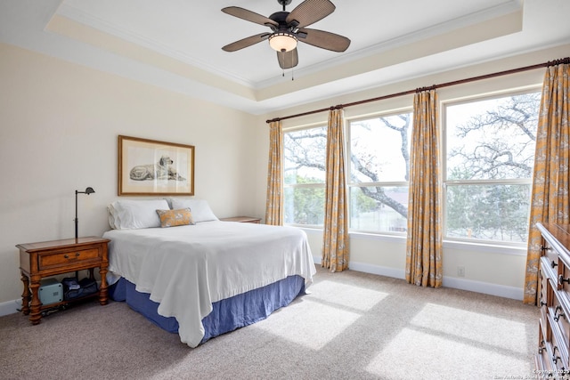 bedroom featuring light carpet, baseboards, a raised ceiling, ceiling fan, and ornamental molding