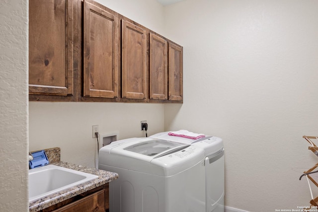 clothes washing area with independent washer and dryer, a sink, and cabinet space