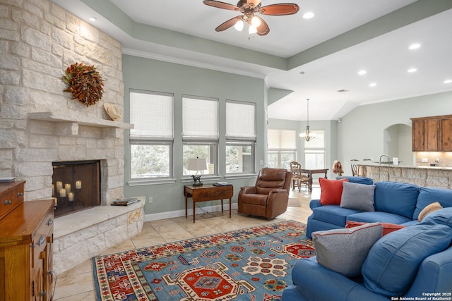 living room with light tile patterned floors, baseboards, ceiling fan with notable chandelier, a stone fireplace, and recessed lighting