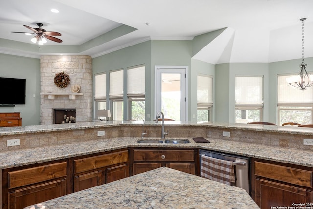 kitchen with light stone counters, open floor plan, dishwasher, and a sink