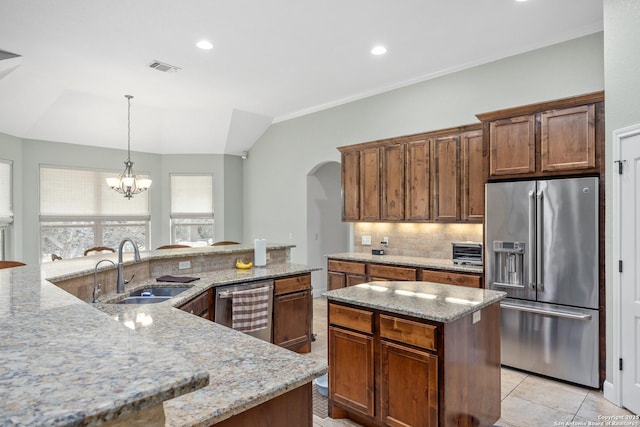 kitchen with arched walkways, stainless steel appliances, a spacious island, decorative backsplash, and a sink