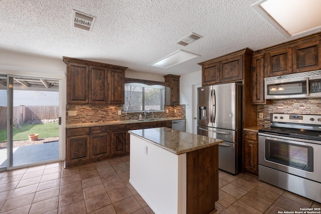 kitchen with visible vents, a kitchen island, appliances with stainless steel finishes, and a sink