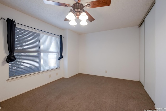 carpeted spare room featuring a ceiling fan and a textured ceiling