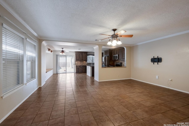 unfurnished living room featuring ceiling fan, ornamental molding, dark tile patterned floors, and baseboards