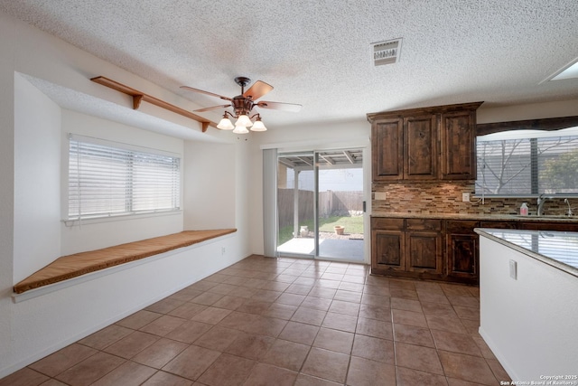 kitchen with light tile patterned floors, visible vents, backsplash, a ceiling fan, and a sink