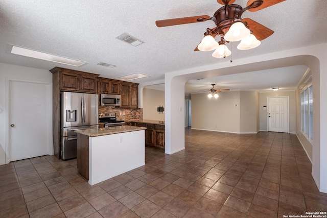 kitchen with a center island, stainless steel appliances, tasteful backsplash, visible vents, and open floor plan