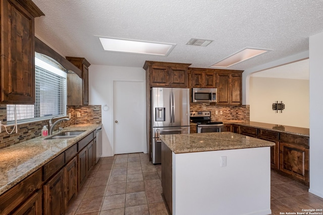 kitchen with light stone counters, visible vents, stainless steel appliances, and a sink