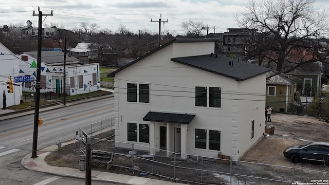 view of front facade featuring a shingled roof, fence private yard, and stucco siding