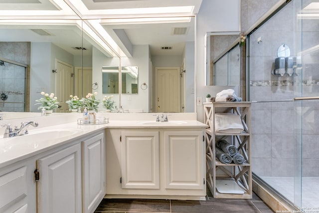 full bathroom featuring visible vents, a sink, a shower stall, and double vanity