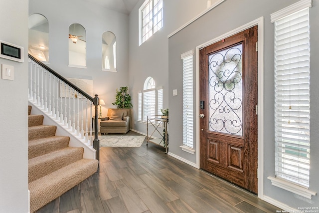 foyer entrance with dark wood-style floors, plenty of natural light, stairs, and baseboards