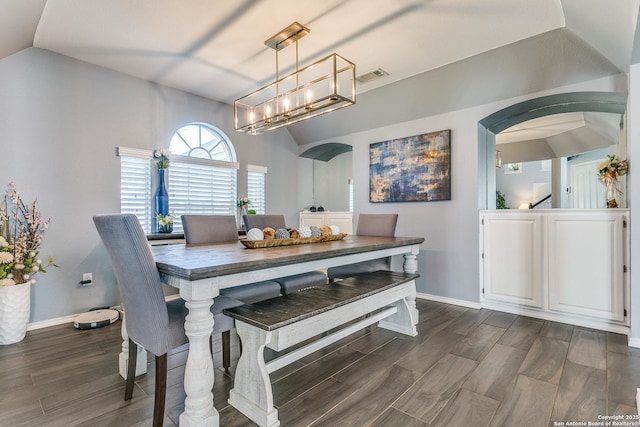 dining room featuring lofted ceiling, dark wood-style floors, visible vents, and arched walkways