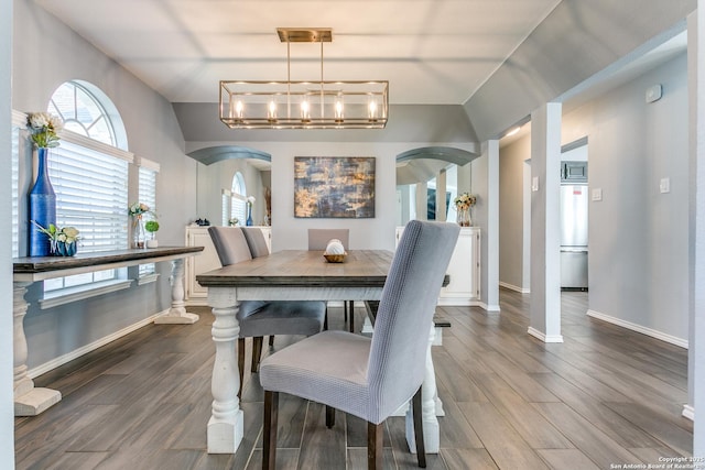 dining room featuring arched walkways, dark wood-style floors, and an inviting chandelier