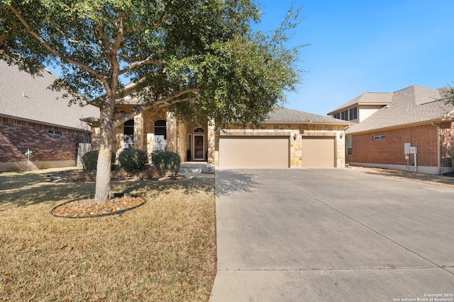 view of front of home featuring a garage, stone siding, concrete driveway, and a front yard