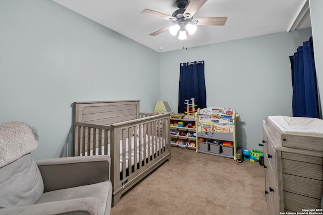 carpeted bedroom with ceiling fan and a crib