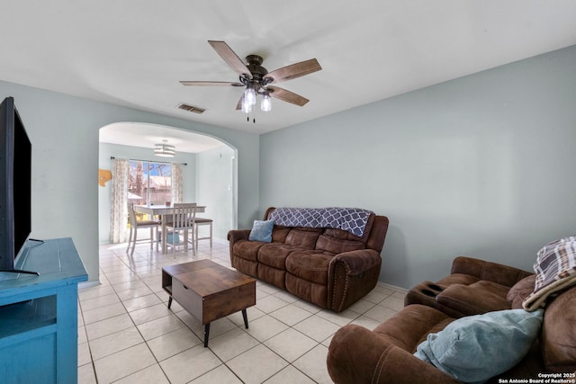 living room with light tile patterned floors, ceiling fan, visible vents, and arched walkways