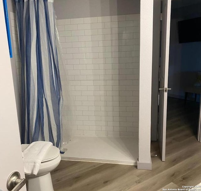 bathroom featuring a stall shower, wood finished floors, and toilet