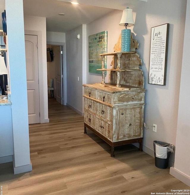 hallway with light wood-type flooring and baseboards