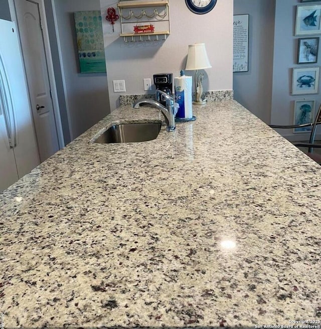 kitchen with light stone countertops, open shelves, a sink, and freestanding refrigerator