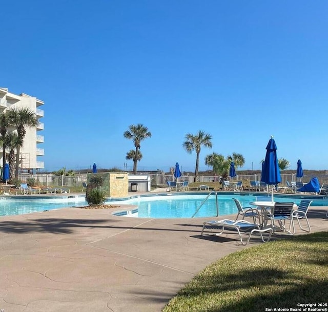 community pool with a patio area and fence