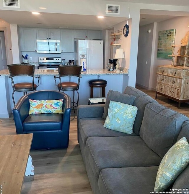 living room with baseboards, visible vents, and wood finished floors