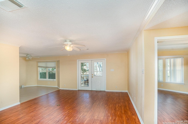 unfurnished room with a wealth of natural light, visible vents, and wood finished floors