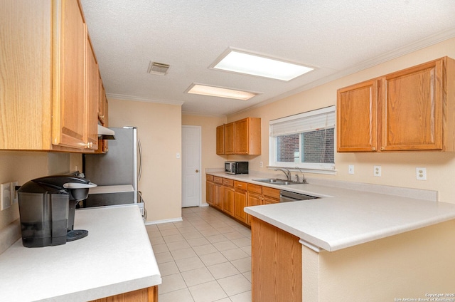 kitchen featuring a peninsula, light countertops, a sink, and visible vents