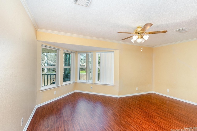 empty room featuring baseboards, visible vents, wood finished floors, and ornamental molding