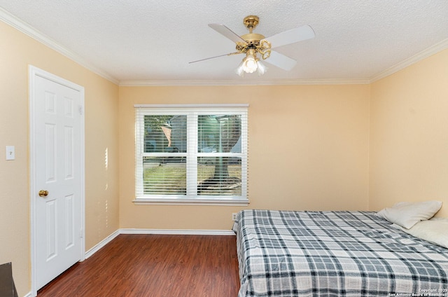 bedroom with a textured ceiling, baseboards, wood finished floors, and ornamental molding