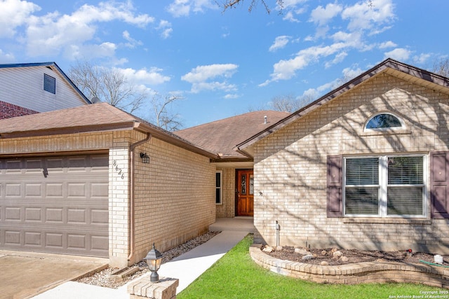 ranch-style home featuring a garage, a shingled roof, and brick siding