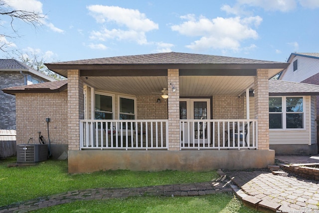 rear view of house with covered porch, brick siding, roof with shingles, and cooling unit