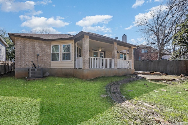 rear view of house featuring brick siding, a yard, and fence