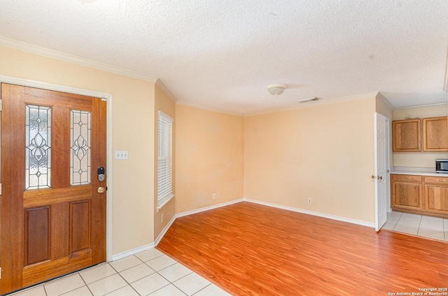 foyer entrance featuring visible vents, crown molding, a textured ceiling, and light wood finished floors