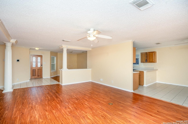 unfurnished living room with light wood finished floors, decorative columns, and visible vents