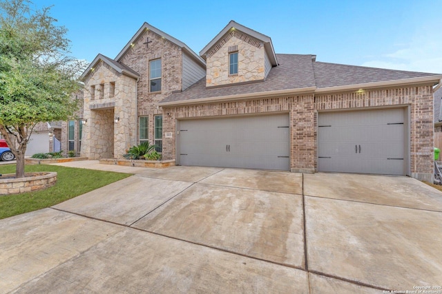 view of front of home with brick siding, roof with shingles, concrete driveway, an attached garage, and stone siding