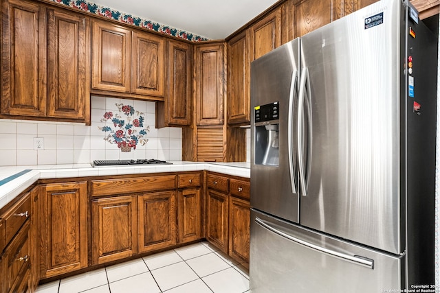 kitchen featuring stainless steel fridge, tile counters, and tasteful backsplash