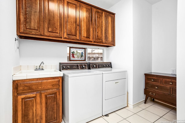 clothes washing area featuring washing machine and dryer, cabinet space, a sink, and light tile patterned floors